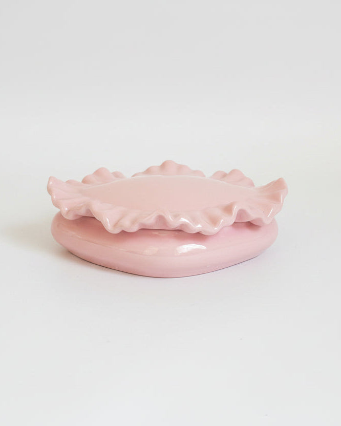 Pink ceramic dish with decorative edge on a white background